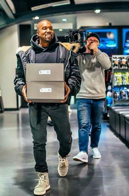 Kanye West carrying two adidas shoeboxes at the Yeezy launch