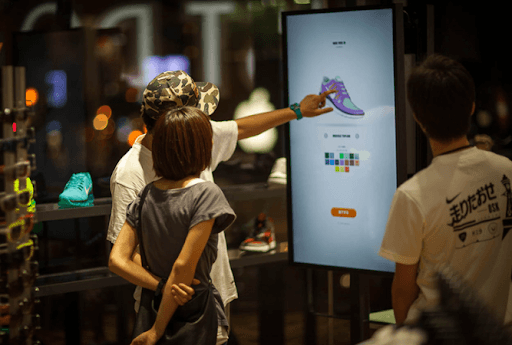 NIKEiD in-store — customer interacting with a large touchscreen configurator kiosk